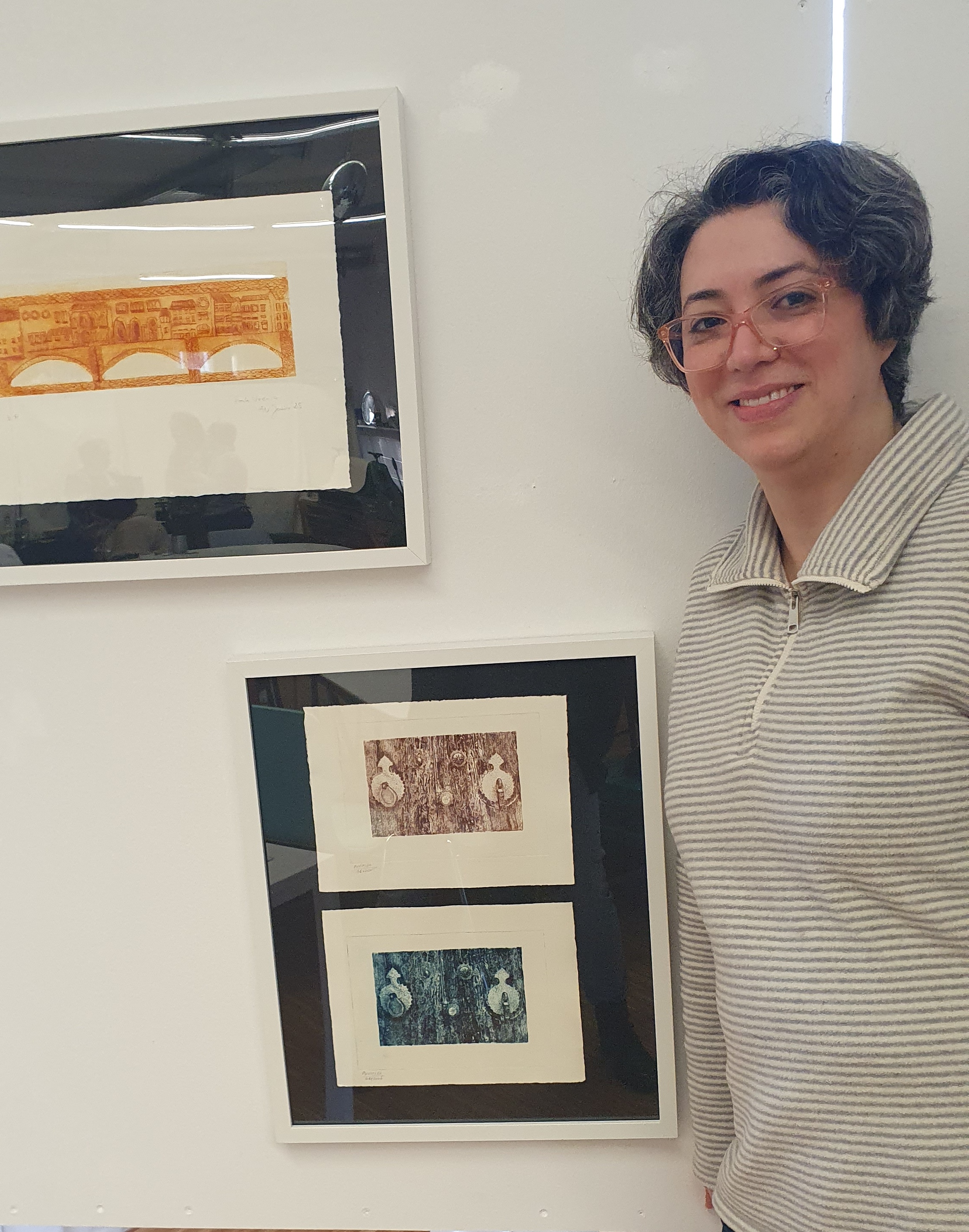 Eine Frau mittleren Alters steht neben zwei Kunstwerken.